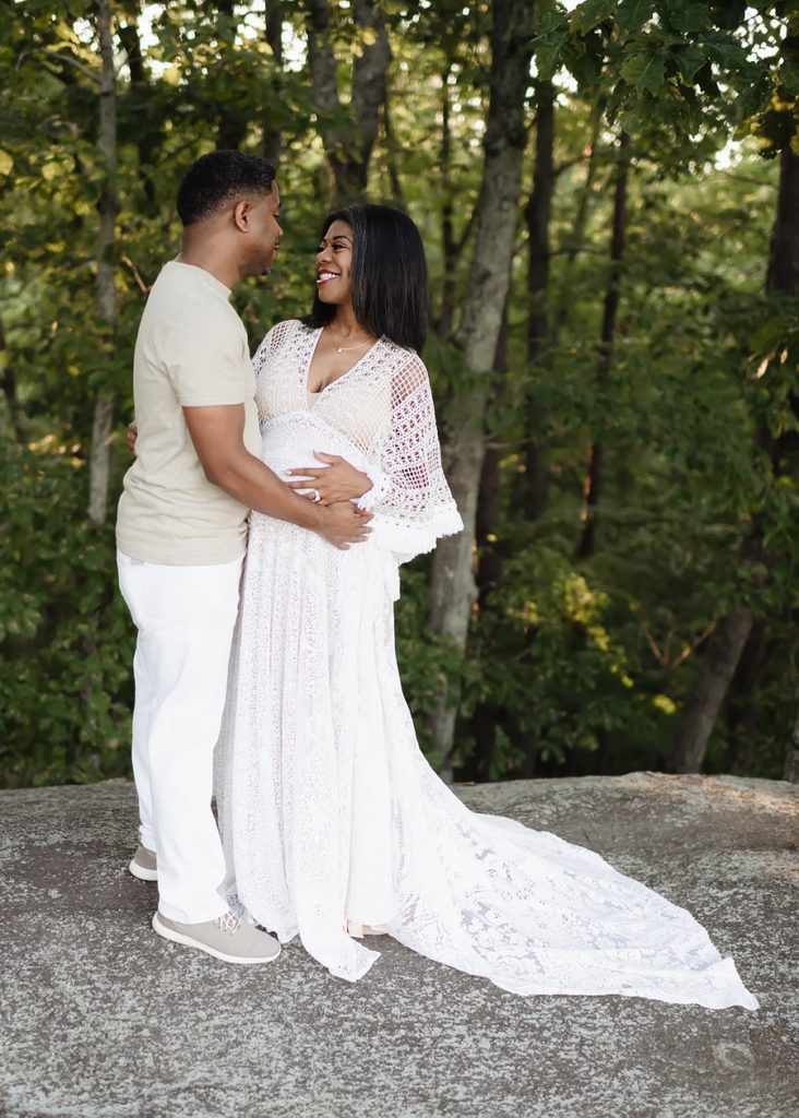 A couple embrace each other in a park for their maternity pictures