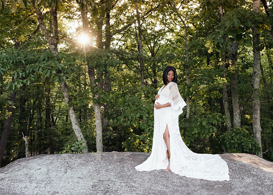 A maternity client holder her bump as she poses at sunset